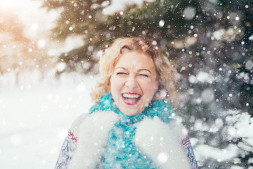 Happy girl laughs playing with snow in a winter snow-covered forest - an emotion of happiness