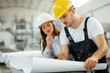 © JustLife - Close up of colleagues working on project in factory.