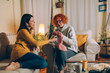 © cherryandbees - mid aged woman friends knitting together and talking at home
