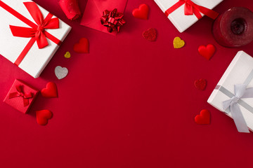 Gift boxes, red paper envelope and red hearts on red background