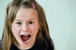 Close up portrait of angry shouting child girl looking aggressively in camera.