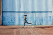 © Marc Bordons/Stocksy - Young runner passing in front of a big blue metal door