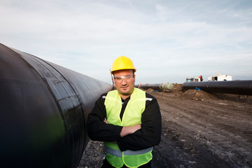 Wall Mural - Portrait of an oilfield worker standing by gas pipe at construction site.