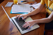 © guille Faingold/Stocksy - Crop girl using laptop at desk with papers