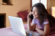 © guille Faingold/Stocksy - Laughing woman with laptop on bed chatting on phone