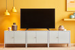 © 365mm/Stocksy - Empty black TV set on white cupboard