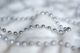 Fototapeta Łazienka - Line of silver beads garland thread chain on a white soft blanket