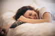 © Chris Zielecki/Stocksy - Young happy tattooed woman lying on a bed and laughing