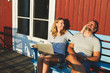 © Maskot - Couple relaxing on bench against cottage