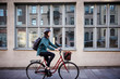 © Maskot - Side view of female engineer riding bicycle on street by building in city