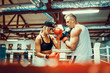 © zamuruev - Young woman exercising with trainer at boxing and self defense lesson.