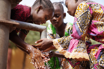 gorgeous african girls washing hands under water tap outdoors