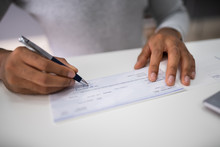 Businessperson's Hand Signing Cheque
