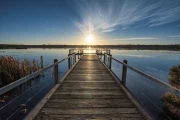 Beautiful wooden pier by the calm ocean with the beautiful sunset over the horizon