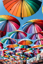 Umbrellas In Rainbow Color On Blue Sky Background