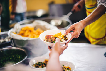 The hands of the poor receive food that volunteers share to alleviate hunger: the concept of donating food to the poor