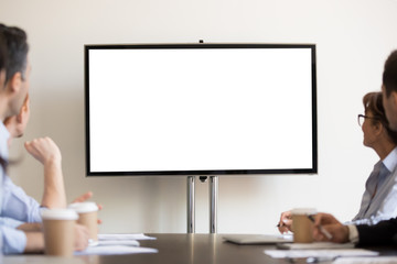 Businesspeople sitting in boardroom looking at tv with white blank