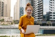 Young Woman sitting in Dubai Marina aria and work on laptop. Student or  freelancer lifestyle.
