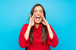 © luismolinero - Young woman with red sweater over isolated blue background shouting with mouth wide open