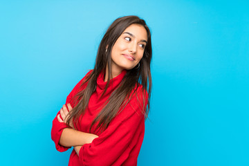 Wall Mural - Young woman with red sweater over isolated blue background laughing