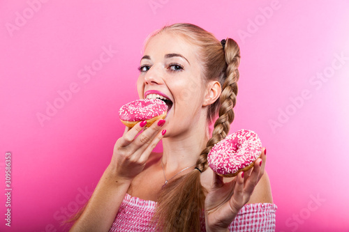 Cuadros en Lienzo sweet tooth blonde with pink donuts posing against pink backdrop in photo studio
