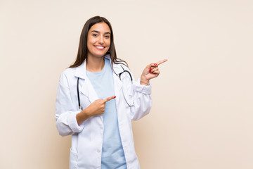 Young doctor woman over isolated background pointing finger to the side