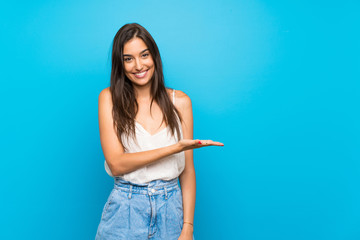 young woman over isolated blue background smiling with a happy and pleasant expression