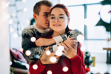 Embracing happy couple in sweaters enjoying Xmas holiday at home