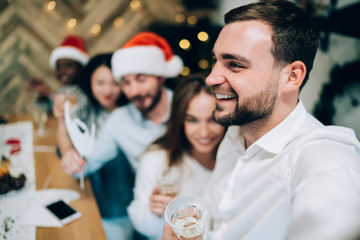 Wall Mural - Joyful man with blurred friends on Christmas party