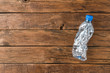 Empty and crushed bottle of water on rustic wooden background with copyspace. Plastic recycling concept