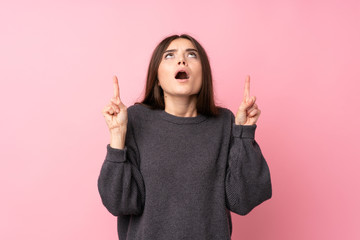 Wall Mural - Young woman over isolated pink background surprised and pointing up
