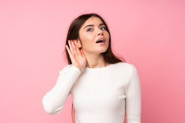 Wall Mural - Young woman over isolated pink background listening something