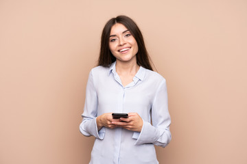 Young woman over isolated background sending a message with the mobile