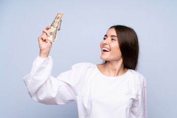 Wall Mural - Young woman over isolated blue background taking a lot of money