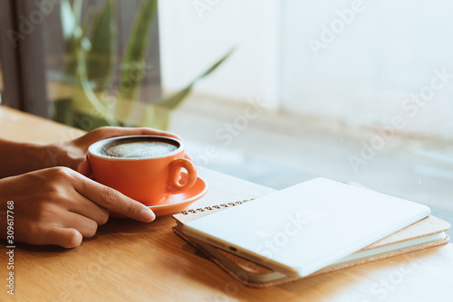 Cuadros en Lienzo Close up hand is holding Orange coffee cup or hot espresso