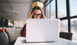 © GalakticDreamer - Young woman in glasses freelance content writer worried about deadlines while sitting with laptop computer in coffee shop, stressed hipster girl learning programming online via modern netbook