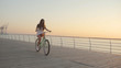 © tol_u4f - Young beautiful woman with a bicycle is having a good time at the sea at sunset or sunrise