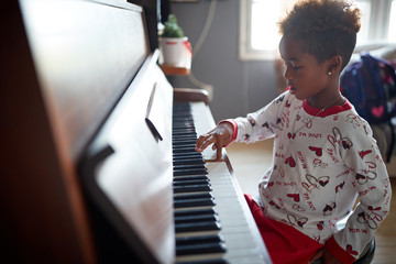 Wall Mural - African American girl play music at piano on Christmas Day.