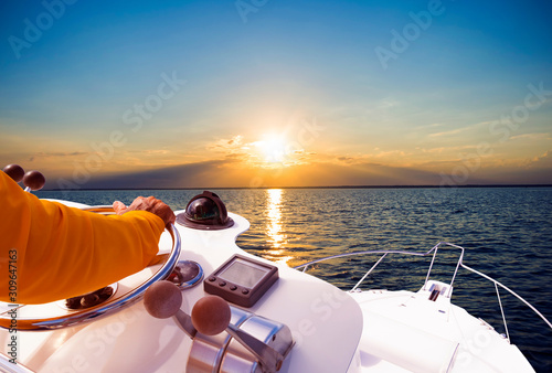 Fotografía Hand of captain on steering wheel of motor boat in the blue ocean during the fishery day