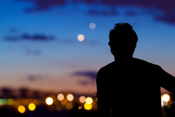 Wall Mural - man looking at the night sky from urban area.