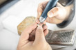 Dental technician grinding implant crown with dental bur at the laboratory, close-up view