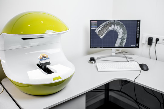 Scanning jaw model on the 3rd scanner in the laboratory, for the manufacture of dentures or implants, computer with imprints on the background