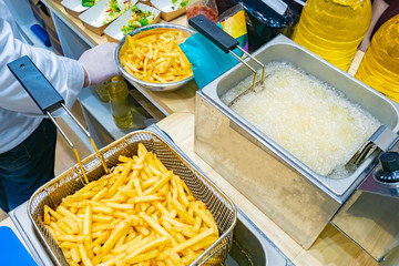 Cooking potatoes in a deep fryer. Industrial deep fryer for cafe. Fast food. Deep-fried vegetables. Frying potatoes in boiling oil. Fries. A side dish of potatoes. Equipment of restaurants.