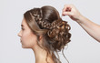 Portrait of a beautiful sensual light brown haired woman with a wedding hairstyle in a beauty salon. The hairdresser does the hairstyle. Wedding hairstyle.