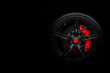 Isolated generic sport car wheel with red breaks drifting and smoking on a black background