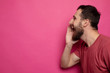 © lashkhidzetim - Side view photo of young bearded man making important announcement on pink background. Copyspace.
