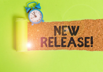 Conceptual hand writing showing New Release. Concept meaning announcing something newsworthy recent product Alarm clock and torn cardboard on a wooden classic table backdrop