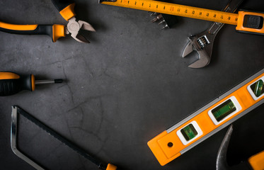 set of black and orange tools on black concrete background