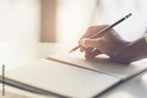 Cuadros en Lienzo Close up of male hand writing with pencil on the book
