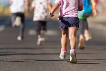 Wall Mural - Running children, young athletes run in a kids run race,running on city road detail on legs